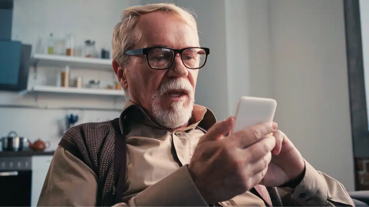 senior man with glasses using mobile