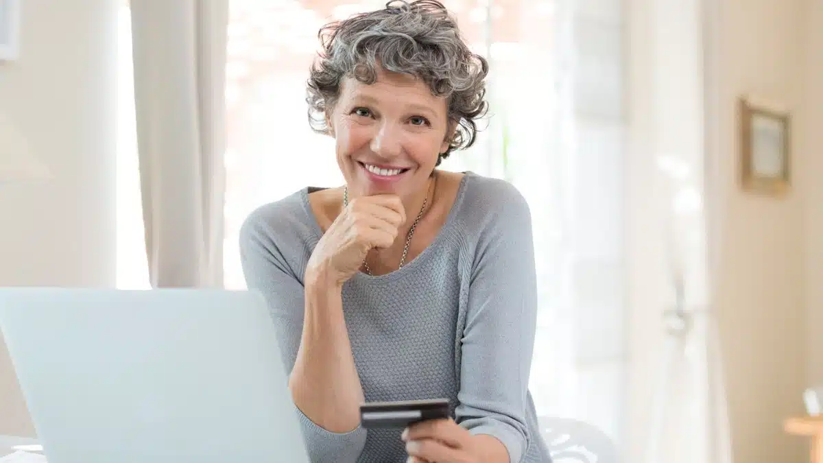 15 Remote Gigs Ideal for Adults Over 60 senior woman with laptop holding credit card